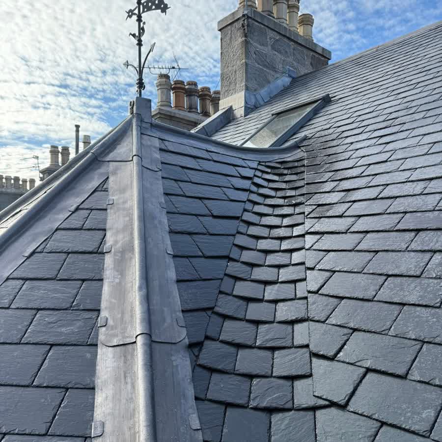 Natural slate roof with a hand dressed lead ridge and an iron weathervane