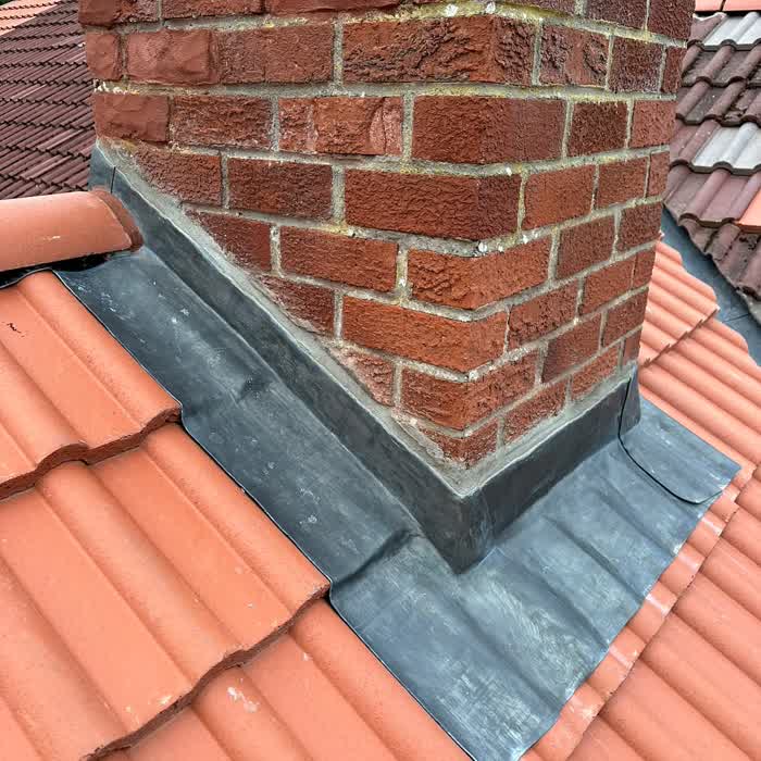 Newly dressed lead flashing and soakers around a brick chimney stack