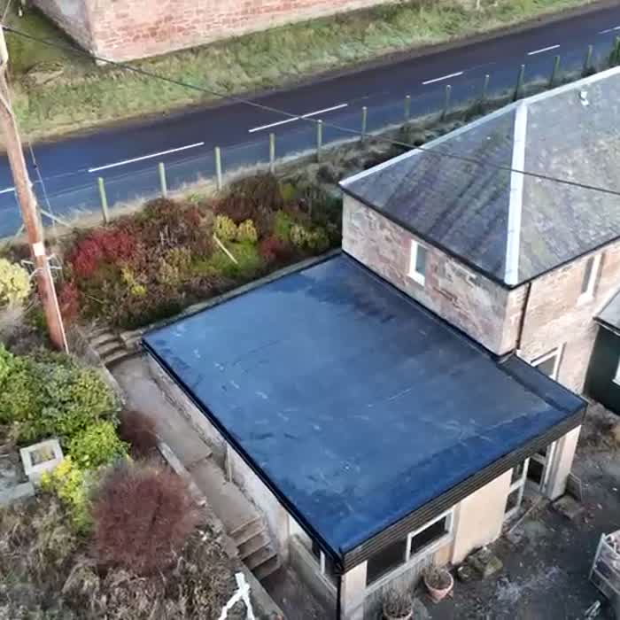 Aerial view of a completed rubber flat roof on a stone cottage extension