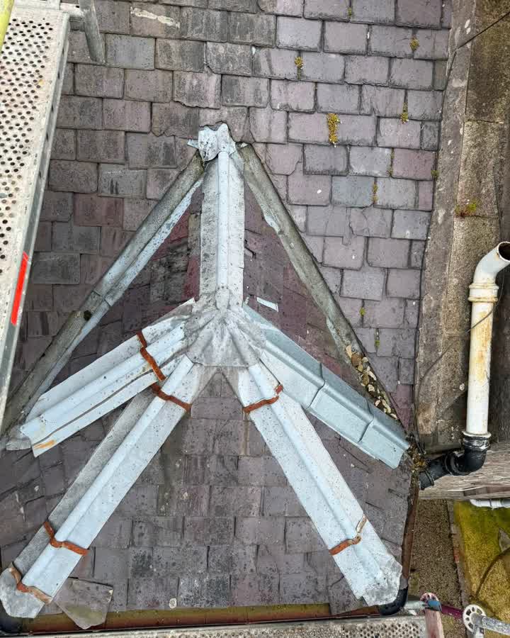 Dormer apex with cracked slates, moss and corroded metal ridge capping before the repair